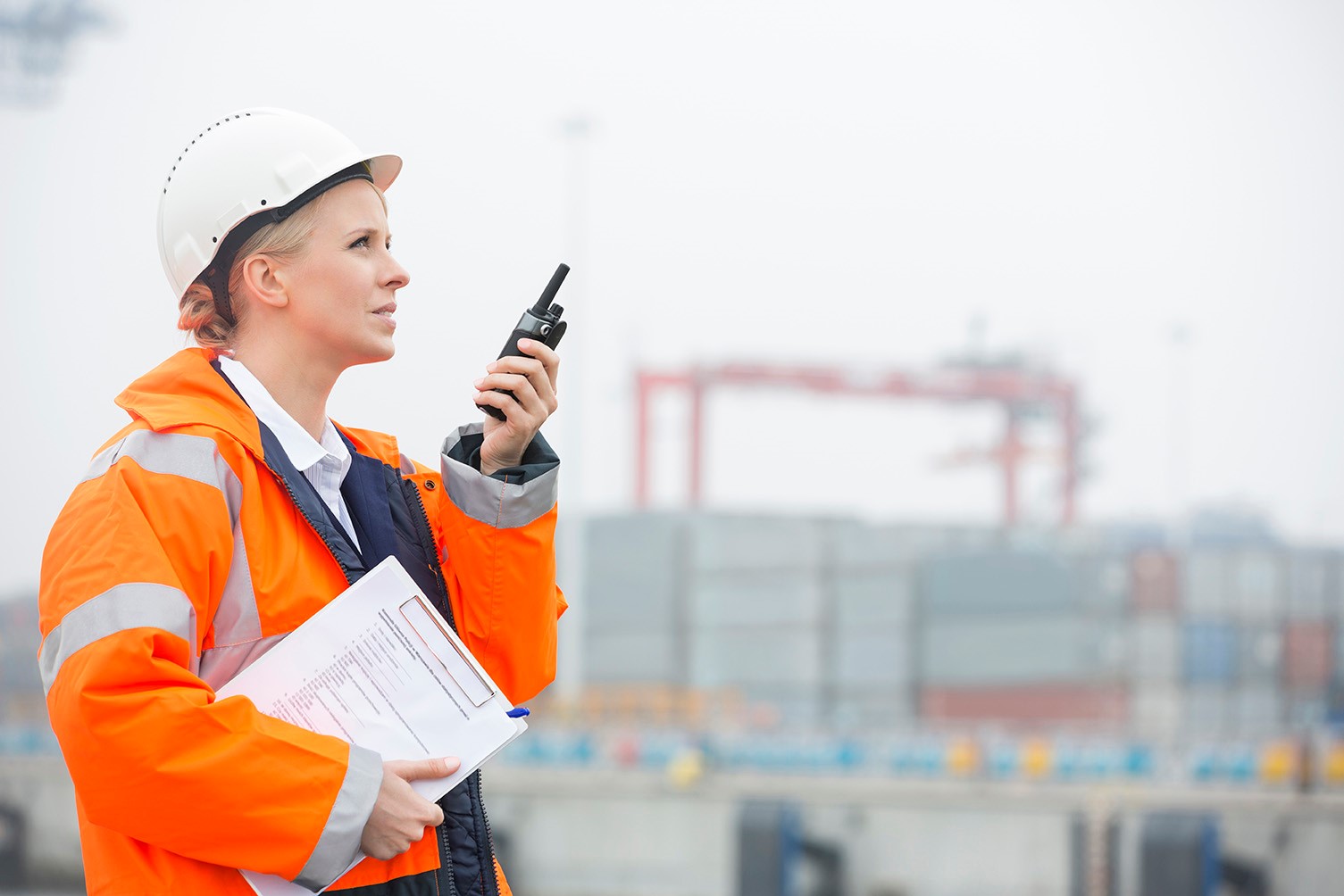 Worker talking on walkie talkie at a work site.